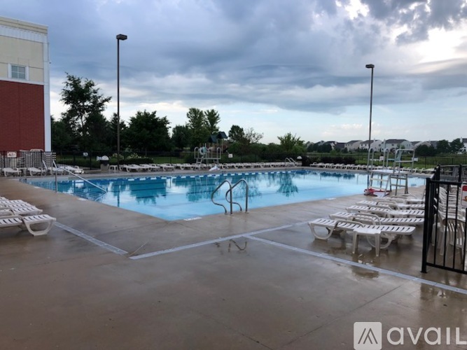 A pool with chairs around it and a cloudy sky.