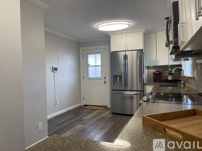 A kitchen with a refrigerator, sink, and cabinets.
