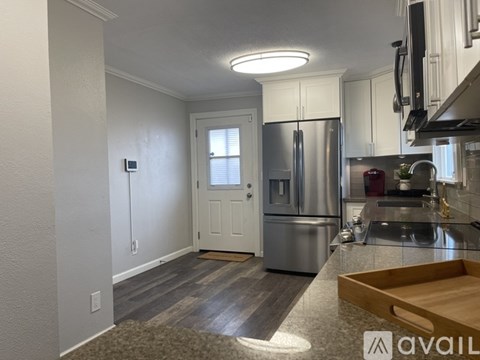 A kitchen with a refrigerator, sink, and cabinets.