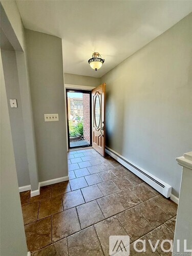A hallway with tiled flooring and a light fixture on the ceiling.