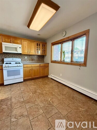 A kitchen with brown tile flooring and wooden cabinets.