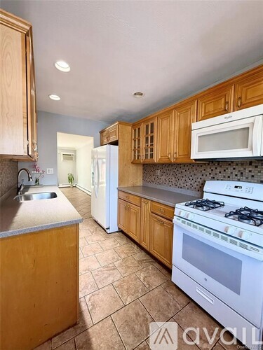 A kitchen with white appliances and wooden cabinets.