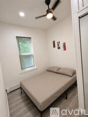A bedroom with a bed, a window, and a ceiling fan.
