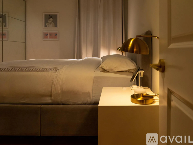 A bedroom with a bed, nightstand, and lamp.