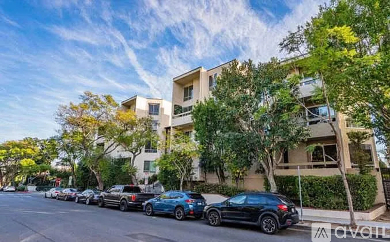 Cars parked in front of a building with trees on the side.