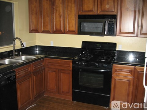 A kitchen with black appliances and wooden cabinets.