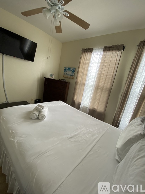 A bedroom with a white bed and a ceiling fan.