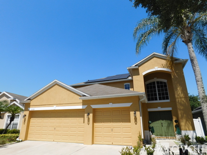 A yellow house with a palm tree in front.