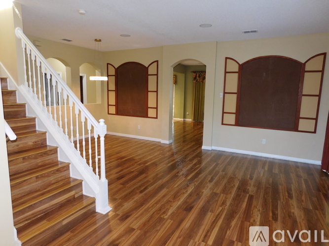 A spacious room with wooden floors and a staircase.