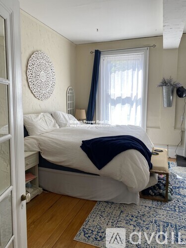 A bedroom with a bed covered in a white and blue comforter.