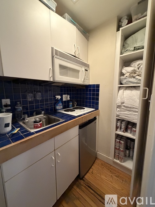 A kitchen with white cabinets and a blue tile backsplash.