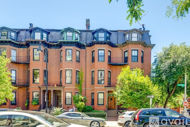 A row of red brick townhouses with green trees in front.