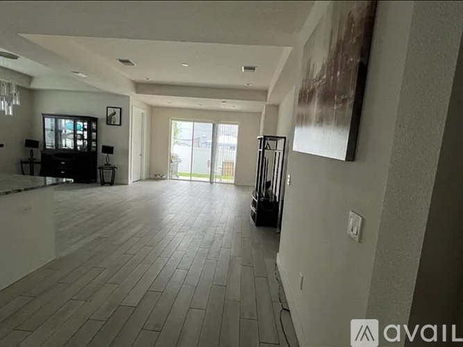 A spacious living room with a wooden floor and a large painting on the wall.