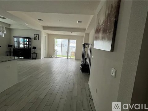 A spacious living room with a wooden floor and a large painting on the wall.