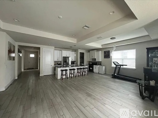 A spacious living room with a kitchen area in the background.