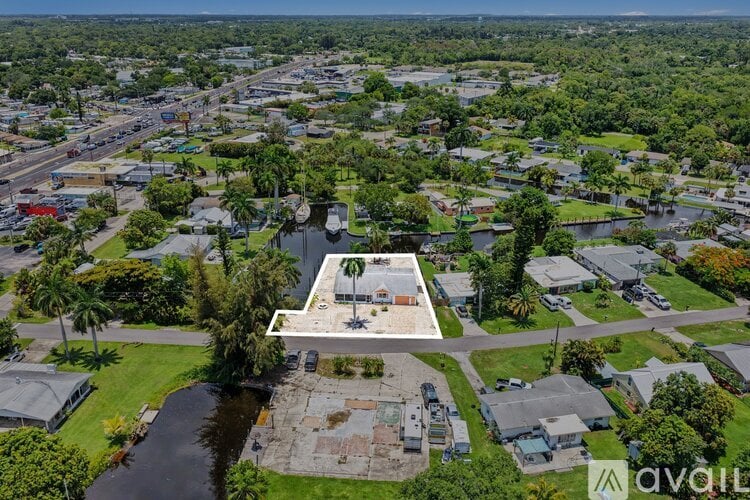 An aerial view of a property with a swimming pool surrounded by trees and buildings.
