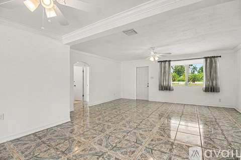 A spacious room with a patterned floor and a window with curtains.