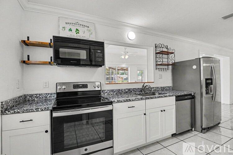 A modern kitchen with white cabinets and black appliances.