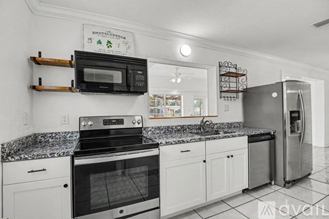 A modern kitchen with white cabinets and black appliances.