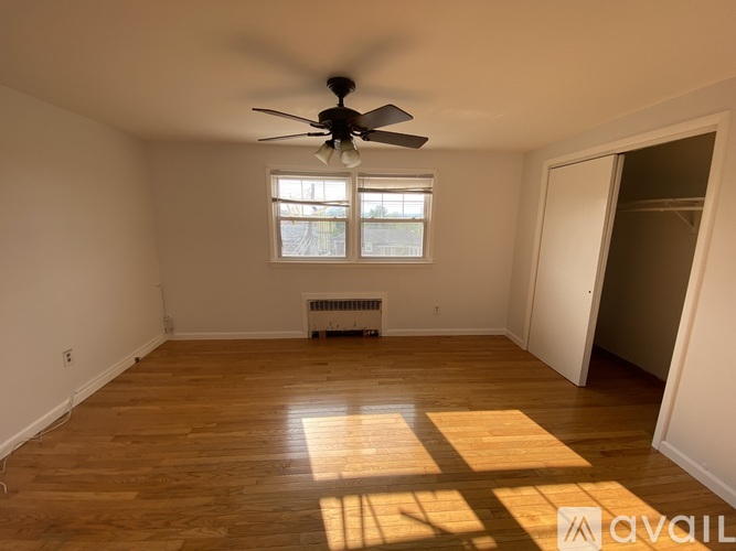 A room with a ceiling fan and a window with sunlight coming through.