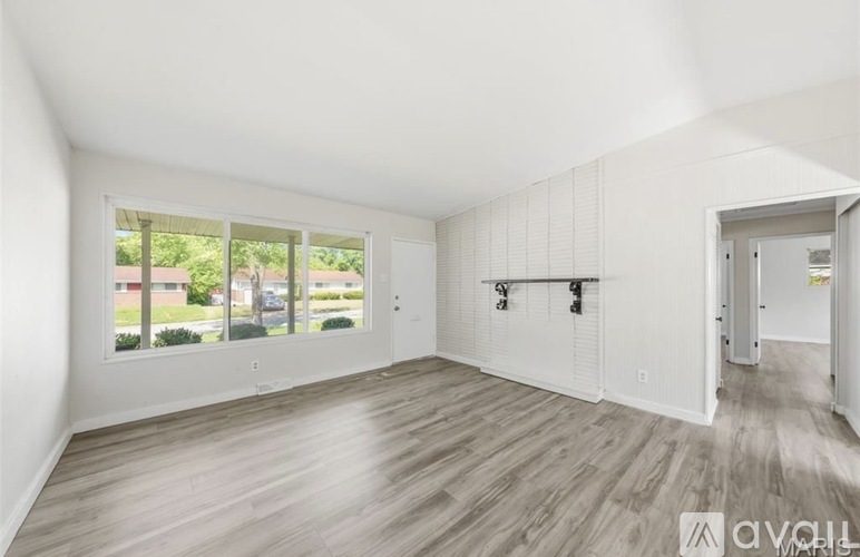 A spacious room with wooden flooring and white walls.