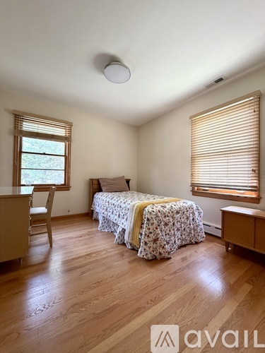 A bedroom with a bed, chair, and window.
