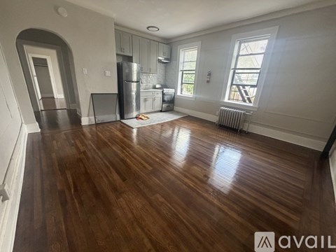 A spacious room with wooden floors and a kitchen area.