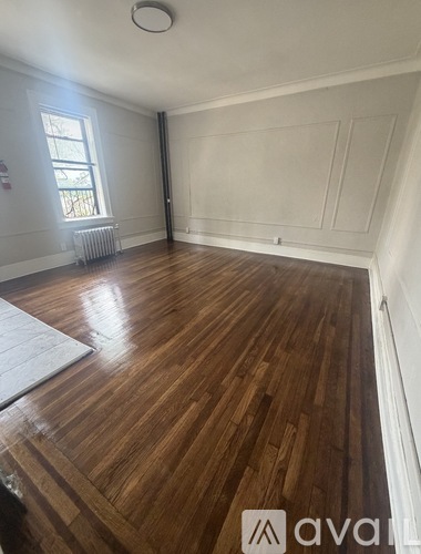 A room with wooden flooring and white walls.