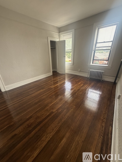 A room with wooden floors and a window with blinds.