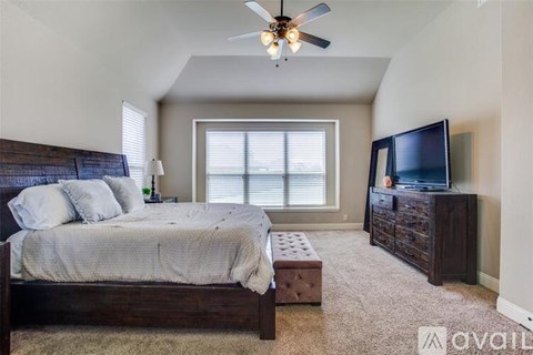 A bedroom with a bed, a dresser, and a ceiling fan.
