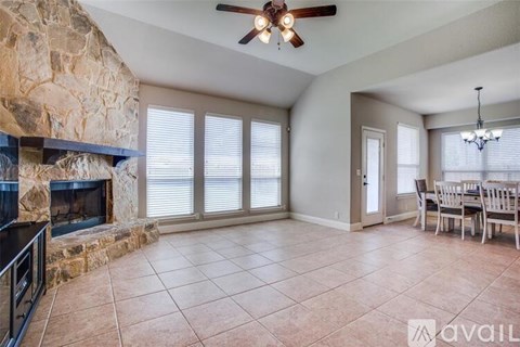 A living room with a stone fireplace and a dining table set up.