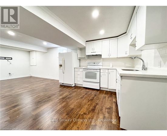 A kitchen with white cabinets and a wooden floor.