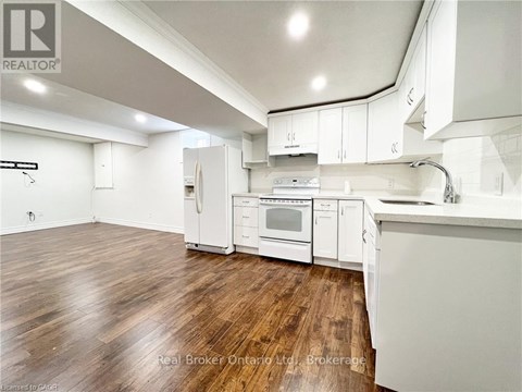 A kitchen with white cabinets and a wooden floor.