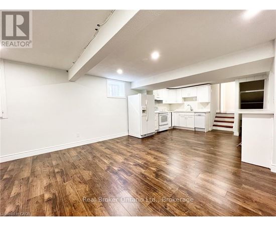 A spacious room with wooden flooring and white walls.