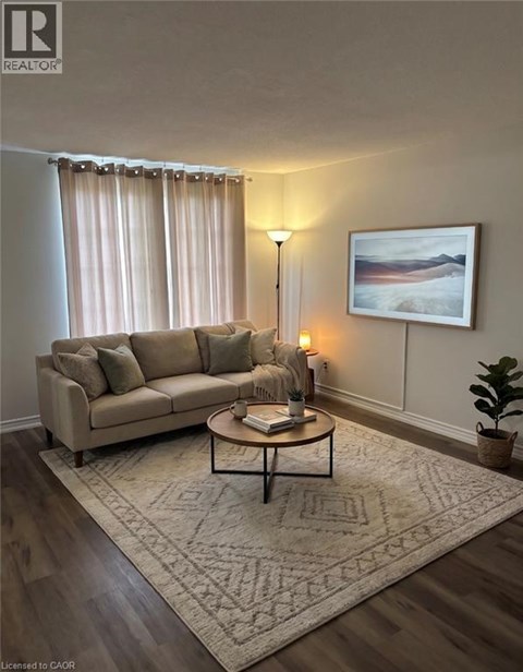 A living room with a beige couch, a coffee table, a lamp, a rug, and a painting on the wall.