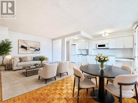 A well-lit dining room with a round table surrounded by chairs.