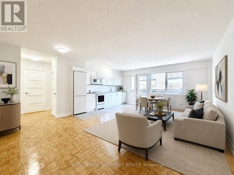 A well-lit living room with a couch, chairs, and a dining table.