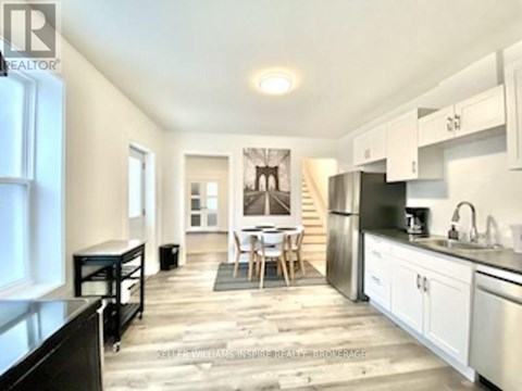 A kitchen with white cabinets and a black refrigerator.