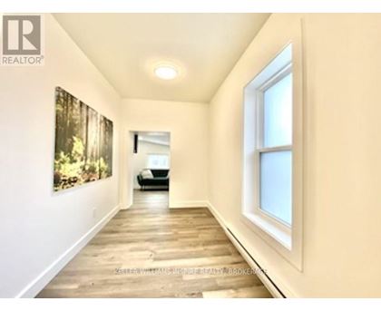 A hallway with a painting on the wall and a car in the background.