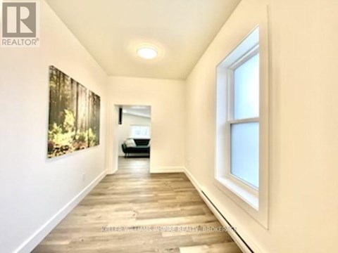 A hallway with a painting on the wall and a car in the background.