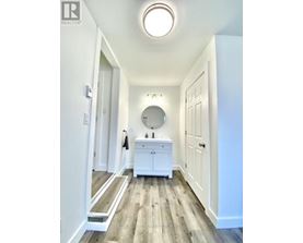 A white bathroom with a round mirror and a wooden floor.