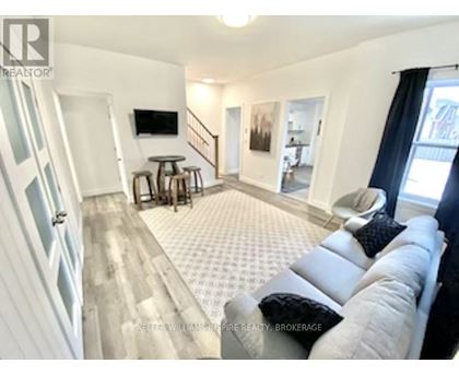 A living room with a grey couch and a television on the wall.