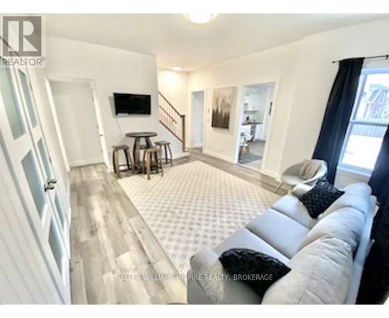 A living room with a grey couch and a television on the wall.