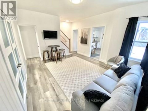 A living room with a grey couch and a television on the wall.