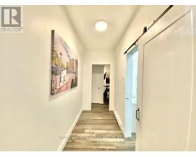 A hallway with a painting on the wall and a person standing in the distance.