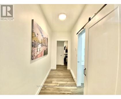 A hallway with a painting on the wall and a person standing in the distance.