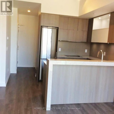 A modern kitchen with dark wood floors and white countertops.