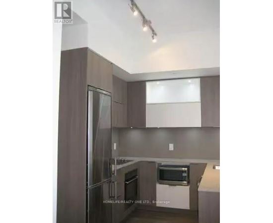 A modern kitchen with a refrigerator, oven, and microwave.