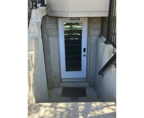 A white door with a glass window is in a stone wall.