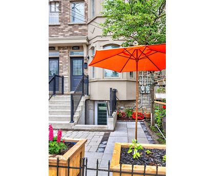 A bright orange umbrella is in front of a building with a black gate.